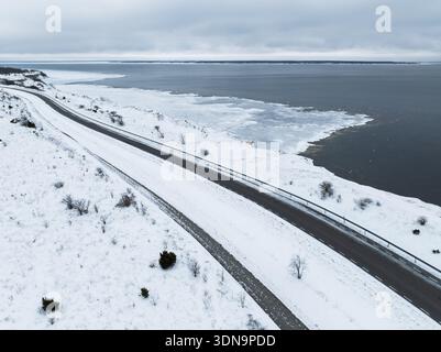 Luftaufnahme einer malerischen Küstenstraße entlang der steilen Kalksteinklippen in Paldiski Estland während eines kalten Winters. Stockfoto