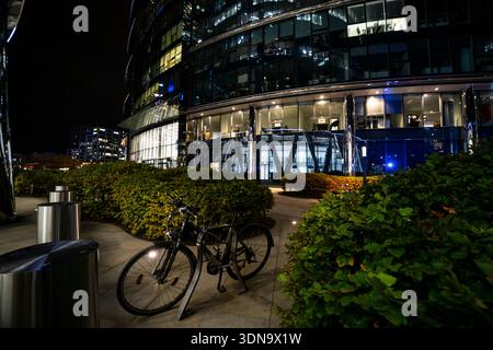 Nächtliche Straßenszene in Warschau, Polen, mit einem Fahrrad, das unter warmen Lichtern der Stadt geparkt wurde. Urbane Atmosphäre mit stimmungsvollen Tönen und europäischer Architektur im Stockfoto