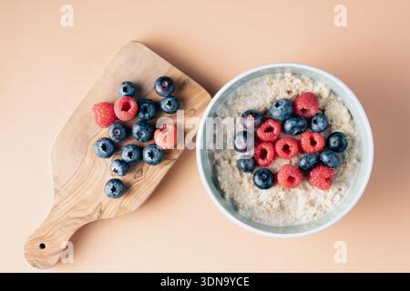 Blick auf ein morgendliches Abendessen mit Haferschüssel und frischem Obst auf einem rustikalen Holzbrett Stockfoto