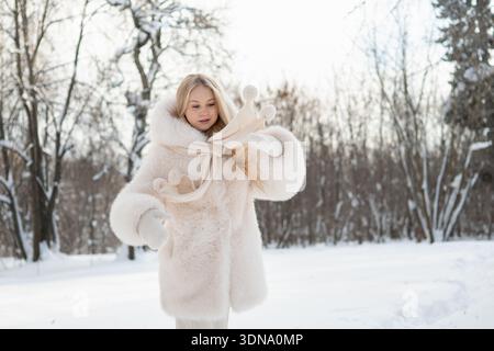 Frau spielt mit Schal im verschneiten Winterpark Stockfoto