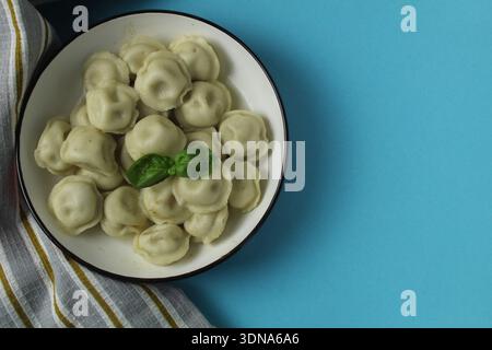 Knödel in einem Teller auf blauem Hintergrund mit Platz für Text im Copyspace-Bereich von oben nach oben. Studio-Aufnahmen von Essen, hausgemachten Gerichten. Stockfoto