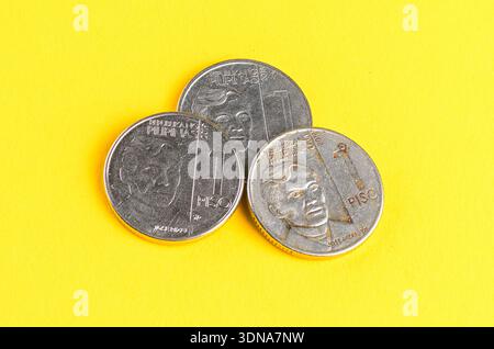 Drei philippinische ein-Peso-Münzen auf hellgelbem Hintergrund Stockfoto