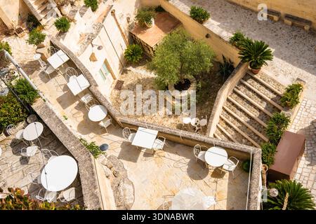 Blick aus der Vogelperspektive auf ein bezauberndes Café im Innenhof, umgeben von alten Mauern, Apulien, Italien Stockfoto