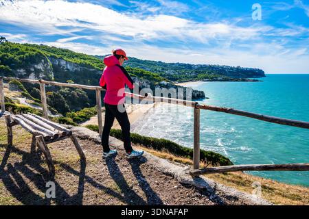 Weibliche Wanderer bewundern die türkisfarbene Bucht mit Zajana Strand und bewaldeten Klippen in der Nähe von Peschici an der Gargano Küste, Apulien, Italien Stockfoto