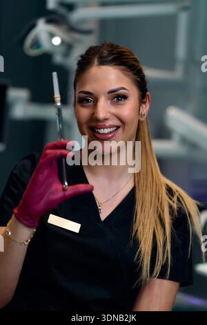Lächelnde Zahnarztassistentin Hält Spritze In Handschuhen In Der Modernen Zahnklinik Für Patientenversorgung Stockfoto