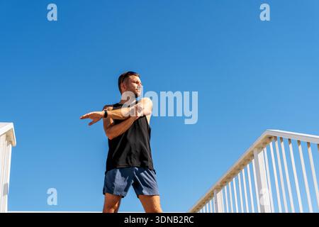 Junger Erwachsener, der sich vor einem Workout im Freien aufwärmt, Stockfoto