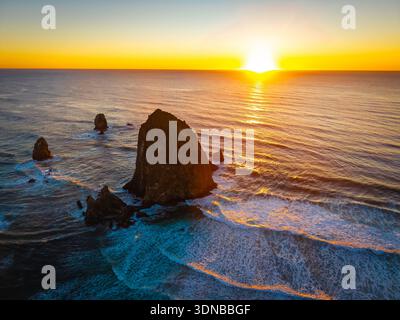 Ein atemberaubender Blick aus der Luft auf Haystack Rock und die Cannon Beach Küste, getaucht in das warme, goldene Licht eines lebendigen Sonnenuntergangs über dem Pazifik Stockfoto