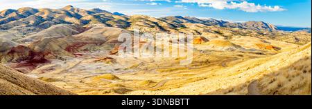 Lebendiger Panoramablick auf die leuchtenden roten, goldenen und schwarzen Schichten von Painted Hills von einem erhöhten Aussichtspunkt am John Day Fossil Beds National Monument bei Sonnenaufgang Stockfoto