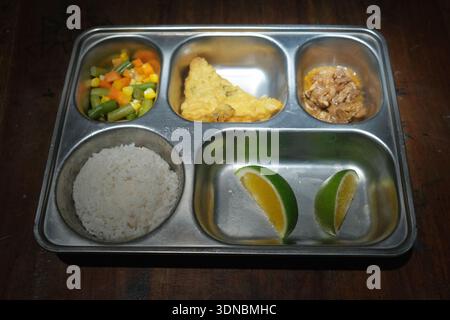 Eine nahrhafte Lunchbox bestehend aus Reis, Tempeh, Fleisch, Gemüse und Orangen. Stockfoto