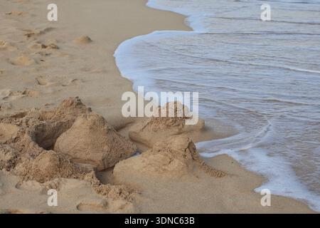 Nahaufnahme einer Sandburg am Strand, wo Meereswellen fließen Stockfoto