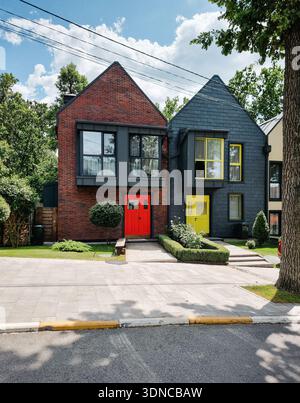 Bunte Stadthäuser nebeneinander. Straße mit modernen kleinen Häusern an einem sonnigen Tag. Neuer Bezirk im Vorstadtbereich. Stockfoto