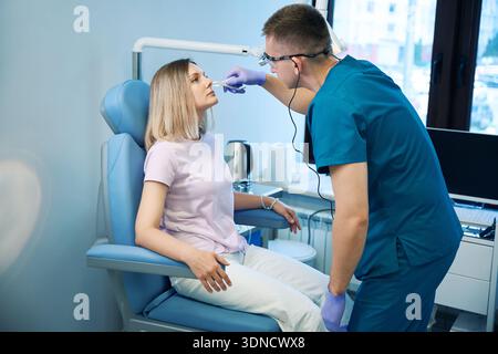 Junger männlicher hno-Arzt, Nasenuntersuchung bei weiblicher Patientin Stockfoto