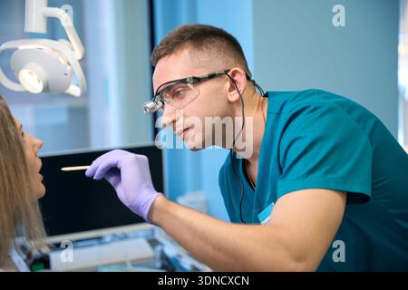 HNO-Arzt mit Inspektionsspachtel zur Untersuchung der Kehle junger Frauen Stockfoto