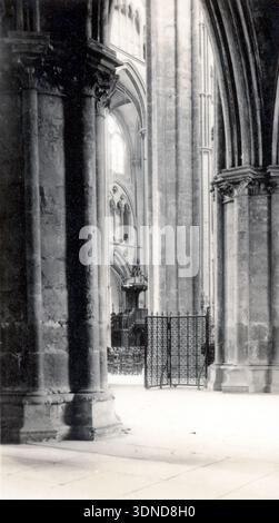 Hohe Säulen ragen unter gerippten Gewölben hervor und bilden geschwungene Spitzbögen, die das Auge durch das weite Innere nach oben ziehen. Eine schmiedeeiserne Barriere umschließt einen Teil des Kirchenschiffs, während eine erhöhte Kanzel dahinter steht. Weiches Licht wird durch hohe Fenster gefiltert in dieser Innenansicht der Kathedrale von Bourges aus dem Jahr 1927. Aus einer Sammlung einzigartiger Fotografien des 20. Jahrhunderts. Amateurfotograf, Schnappschüsse und einige größere in einem einzigen Album, das die Reisen einer Familie in Europa dokumentiert. Stockfoto