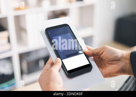 Hände, die das Smartphone halten, um Papierdokumente mit mobiler App-Schnittstelle zu scannen, digitale Verifizierung für das Fintech-Onboarding, QR-Check-in, E-Signatur, Mod Stockfoto