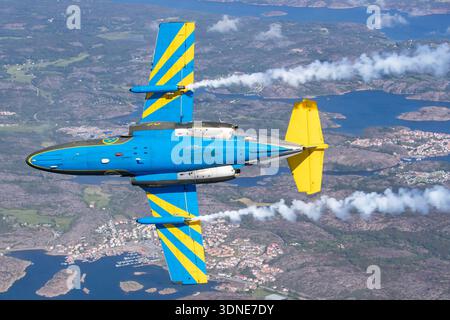 Der Saab SK 60A ist in dieser Ansicht auf der Unterseite in einem Kunstflug-Luft-Rauchdisplay zu sehen. Die zweimotorige, hochflügelige Jet-Trainer-Variante der Saab 105-Familie diente in Flygvapnet-Trainings- und Verbindungspositionen. Er verfügt über ein T-Tail, zwei Turbofan-Motoren mit Maschinenhäusern und strukturelle Details, die unter dem Rumpf und den Tragflächen sichtbar sind. Das historische Flugzeug trägt die schwedischen Classic Jets-Farben als Teil einer Kunstflugroutine. Stockfoto