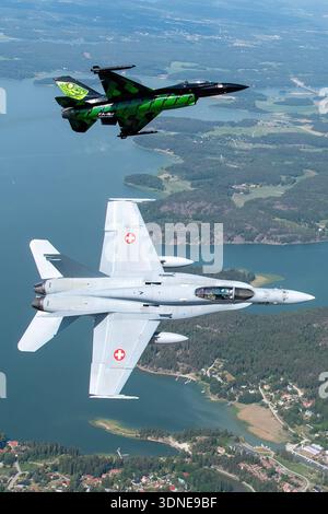 Der belgische F-16AM-Kampf gegen Falcon 'Dream Viper' (FA-87, 6H-87) und der Schweizer F/A-18C Hornet (J-5008, 1336/SFC008) führen Kunstflugmanöver durch, einschließlich Banking, Formation und Einzelausstellungen während der Turku Airshow 2023 in Finnland. Die F-16AM verfügt über einen einzelnen Pratt & Whitney F100-PW-220 Turbofan; die F/A-18C hat zwei General Electric F404-GE-402-Motoren. Die Bilder zeigen Cockpit, Rumpf, Flügelkonfiguration, Heckdesign, Lackierung, und Unterseiten während der Luft-Luft-Flugvorführung. Stockfoto