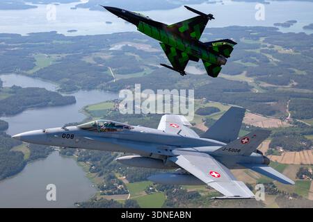 Belgische F-16AM 'Dream Viper', Reg. FA-87 und Swiss F/A-18C Hornets, Reg. J-5008, Kunstflug mit Bank- und Unteransicht auf der Turku Airshow 2023. Flugzeuge verfügen über eine niedrige Flügelkonfiguration, Luftblase, Multifunktionsfähigkeit, individuelle Lackierung, Heckkunst, Rumpf, Steuerflächen, Flügelspitzen-Manövrieren und fortschrittliche Avionik. Air-to-Air-Display betont Flugleistung, Manövrierfähigkeit und Demonstrationsmöglichkeiten in der öffentlichen Luft. Stockfoto