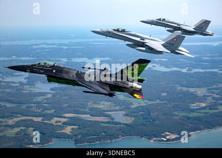 Die Szene zeigt belgische und Schweizer Luftwaffenjets, die während der Turku Airshow 2023 in Finnland eine Luft-Luft-Formation durchführen. Der belgische F-16AM Fighting Falcon FA-87 trägt die spezielle Lackierung von Dream Viper und wird von einem Pratt und Whitney F100-PW-220 Turbofan angetrieben. Die Schweizer F/A-18C Hornets J-5008 und J-5016 sind mit zwei General Electric F404-GE-402 Turboventilatoren ausgestattet. Sichtbare Elemente sind Cockpit-Rahmen, Heckkunst, nationale Markierungen und synchronisierter Kunstflug. Stockfoto