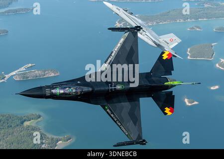 F-16AM Kämpfer Falcon 'Dream Viper' (FA-87, 6H-87) der belgischen Luftwaffe und der Schweizer F/A-18C Hornet (J-5008, 1336/SFC008) führen Overhead- und Bankmanöver in Solo- und Formationsflugzeugen auf der Turku Airshow 2023 in Finnland durch. Die F-16AM ist ein einmotoriger Mehrzweckjäger mit Pratt & Whitney F100-PW-220 Turbofan; die F/A-18C wird von zwei General Electric F404-GE-402-Motoren angetrieben. Das Display hebt die Lackierung, die Heckkunst, den Rumpf, das Cockpit, die Flügelstruktur hervor. und Flugsteuerungsflächen während der Luft-Luft-Demonstration. Stockfoto