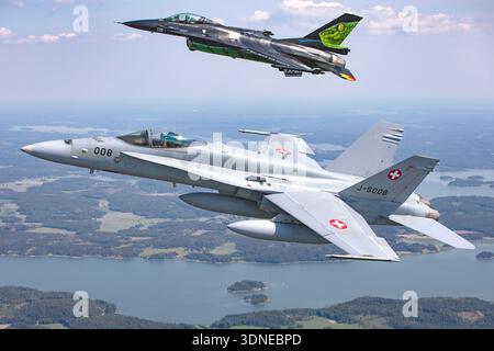 Die belgische Luftwaffe General Dynamics F-16AM Fighting Falcon FA-87 fliegt in enger Formation mit einer Schweizer Luftwaffe McDonnell Douglas F/A-18C Hornet J-5008 während der Flugschau Turku in Finnland 2023. Die F-16AM wird von einem einzelnen Pratt & Whitney F100 Turbofan-Motor angetrieben und trägt die spezielle Dream Viper Displaylackierung mit unverwechselbarem Heckdesign. Der zweimotorige F/A-18C, angetrieben von General Electric F404 Turboventilatoren, trägt Schweizer Standardkennzeichnungen. Beide Flugzeuge werden im kontrollierten Kunstflug als Teil einer offiziellen Anzeigesequenz Luft-Luft gezeigt. Stockfoto
