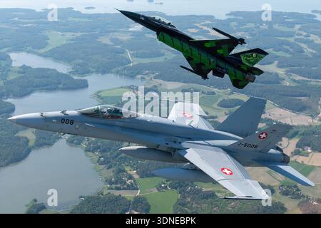 F-16AM Kampffalke „Dream Viper“ (FA-87, 6H-87) der belgischen Luftwaffe und die Schweizer F/A-18C Hornet (J-5008, 1336/SFC008) führen koordinierte Kunstflugmanöver durch, einschließlich Bank- und Formationsmanöver auf der Flugschau Turku 2023 in Finnland. Die F-16AM verfügt über einen einmotorigen Pratt & Whitney F100-PW-220 Turbofan, und die F/A-18C wird von zwei General Electric F404-GE-402-Motoren angetrieben. Die Bilder erfassen Rumpf, Tragflächenkonstruktion, Heckbaugruppe, Haube und Lackierung während Luft-Luft-Vorführungen. Stockfoto