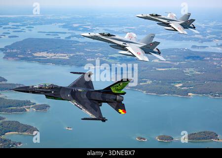 Dieses Bild zeigt die belgische Luftwaffe F-16AM, die den Falcon FA-87, Serie 6H-87, sowie die F/A-18C Hornets J-5008 und J-5016 auf der Flugschau Turku, Finnland 2023, angreift. Beide Flugzeuge verfügen über maßgeschneiderte Lackierungen und Tail Art, die Solo- und Formationsflugzeuge durchführen. Die F-16AM wird von einem Pratt & Whitney F100-PW-220 Turbofan angetrieben, während die F/A-18C Hornets zwei General Electric F404-GE-402-Motoren haben. Nahaufnahmen von Piloten und Luft-Luft-Manöver werden erfasst. Stockfoto