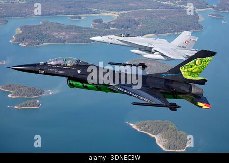 Die belgische Luftwaffe F-16AM Fighting Falcon FA-87 fliegt zusammen mit der Schweizer Luftwaffe F/A-18C Hornet J-5008 während der Turku Airshow 2023 in Finnland in enger Formation. Die F-16AM, angetrieben von einem Pratt & Whitney F100 Turbofan, zeigt die spezielle Dream Viper Lackierung und das Rauchsystem. Die F/A-18C Hornet, ausgestattet mit zwei General Electric F404 Turboventilatoren, behält die Position bei. Die Flugzeuge werden mit einer koordinierten Kunstflugschau gezeigt. Stockfoto