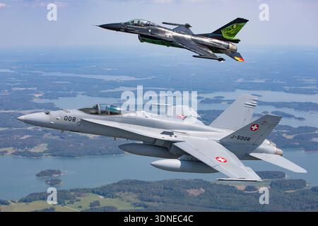 Die belgische F-16AM FA-87 und die Schweizer F/A-18C Hornet J-5008 werden auf der Turku Airshow 2023 gezeigt, die Kunstflugzeuge in Formationen und Einzelflügen durchführen. Beide Flugzeuge verfügen über individuelle Lackierungen und Tail-Art. Der F-16AM wird von Pratt & Whitney F100-PW-220 Turbofan angetrieben, während F/A-18C Hornet zwei General Electric F404-GE-402-Motoren verwendet. Nahaufnahme- und Luft-Luft-Winkel zeigen Cockpit-Details, Manövrieren und Präzisionsfliegen moderner Militärjets. Stockfoto