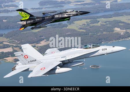 Belgische F-16AM Fighting Falcon 'Dream Viper', Reg. FA-87, Seriennummer 6H-87 und Swiss F/A-18C Hornet, Reg. J-5008, Seriennr. 1336/SFC008, Durchführung von Kunstflugzeugen auf der Turku Airshow 2023 in Finnland. Beide Flugzeuge verfügen über ein Tiefflügel-Design, Luftblase-Baldachin, Tail-Art, individuelle Lackierung, fortschrittliche Avionik, und manövrierbarer Rumpf. Nahaufnahmen von Piloten und Luft-Luft-Fotografien zeigen Bedienflächen, Flügelkonfiguration, Rumpf und Leistung während der öffentlichen Demonstration. Stockfoto