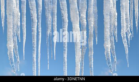 Große sonnenbeschienene Wintereiszapfen auf hellblauem Himmel Hintergrund Stockfoto