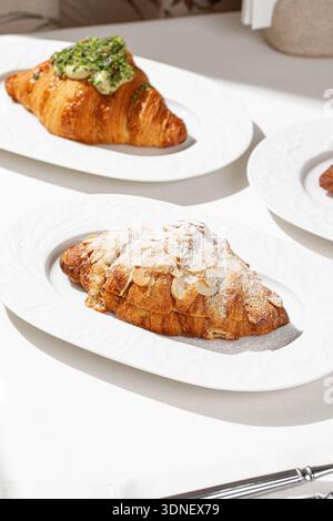 Mandelcroissant und Pistaziencroissant auf Tellern Stockfoto