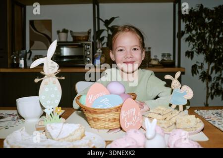 Porträt eines lächelnden Kindermädchens, während er drinnen Ostern feiert Stockfoto