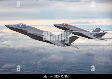 Ein Blick aus der Luft zeigt F-35A Lightning II Flugzeuge der US Air Force, die an den USAFE Days 2023 in Formation fliegen. Dampfspuren erscheinen entlang der Flügel, während die Kämpfer Geschwindigkeit und Höhe halten. Die F-35A ist ein einmotoriges, einsitziges Stealth-Mehrzweckflugzeug mit einem Pratt & Whitney F135-Turbofan-Motor und fortschrittlichen Sensorsystemen. Das Bild hebt die Details des Cockpits und das niedrig beobachtbare Design hervor, das von den US-Luftstreitkräften in Europa betrieben wird. Stockfoto