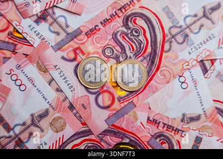 Zwei 1-Euro-Münzen liegen auf Tengescheinen. Währungsumtausch Stockfoto