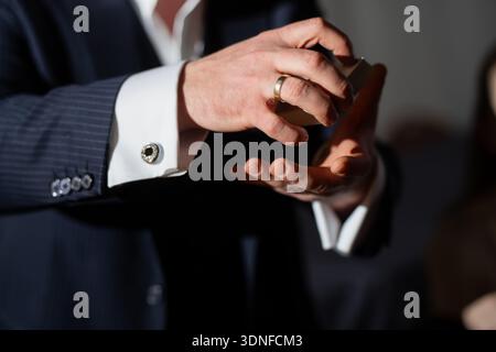 Nahaufnahme von Zauberhänden, die Spielkarten mischen, Anzug Manschettenknöpfe und Goldring sichtbar, dramatische Spotlight Beleuchtung mit flacher Tiefe Hintergrund bl Stockfoto