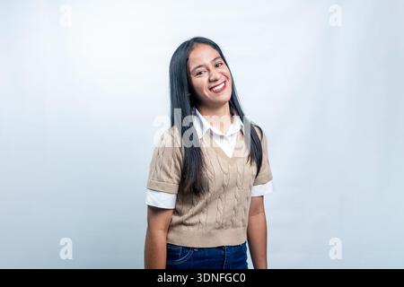 Eine schöne junge indonesische Frau, die mit einem aufrichtigen, freudigen Lächeln in die Kamera schaut. Perfekt für freundlichen Service und Lifestyle-Repräsentationen. Stockfoto