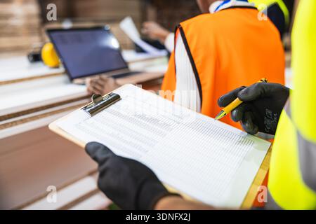 Mitarbeiter, der die Inventarliste im Holzlager überprüft Stockfoto