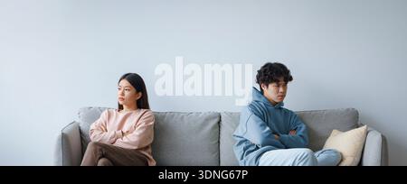 Zwei Personen sitzen während einer Meinungsverschiedenheit auf einer Couch in einem Wohnzimmer Stockfoto