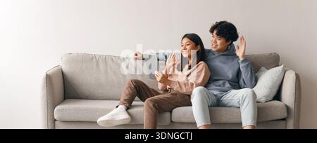 Paare genießen die gemeinsame Zeit auf dem Sofa, während sie das Tablet verwenden Stockfoto
