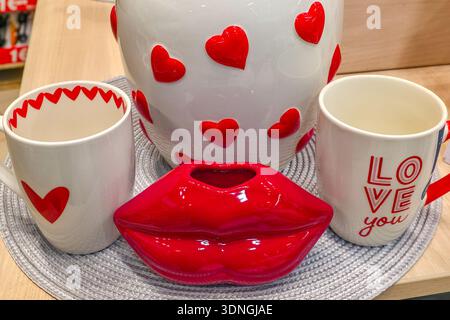Romantisches Stillleben am Valentinstag mit Keramikbecher, Herzmustern und rotem Lippendekor, perfekt für Liebe, Dating, Geschenke und gemütliche Momente zu Hause Stockfoto