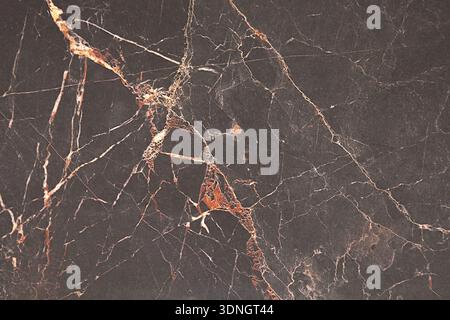 Nahaufnahme einer luxuriösen Oberfläche aus schwarzem Marmor mit komplexen Mustern aus Gold und weißen Adern. Dieser elegante Stein verschönert damit jeden Raum Stockfoto