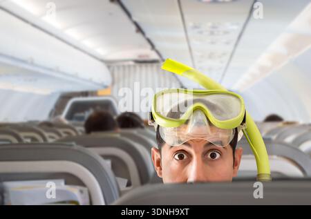 Nahaufnahme eines Mannes mit Schnorchelmaske sieht im Flugzeug überrascht aus Stockfoto