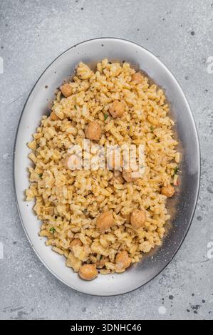 Türkisches Bulgur-Pilaw mit Kichererbsen serviert in Keramikschale mit Blick von oben auf grauem Steinhintergrund mit Kopierraum. Stockfoto