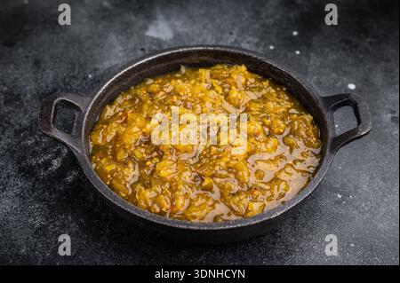 Traditionelle Gurken-Relish mit reichhaltiger Textur serviert in gusseiserner Pfanne auf dunklem Steinboden Gourmet-Hintergrund. Stockfoto