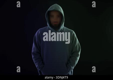 Kriminelle im Hoodie auf schwarzem Hintergrund. Mann mit unerkennbarem verschwommenem Gesicht Stockfoto