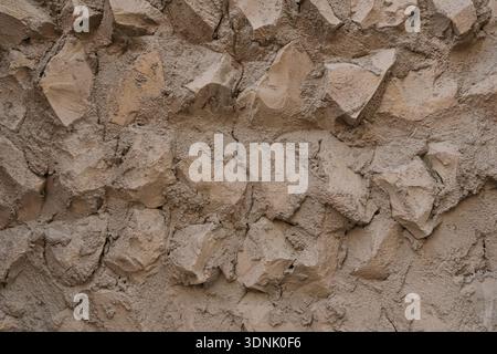 Authentische nahöstliche Steinmauern mit handgefertigtem Putz und natürlichen Felselementen. Warmer neutraler Hintergrund Stockfoto