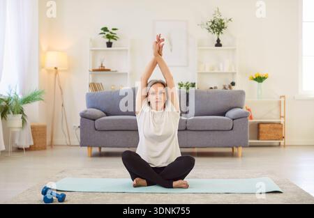Yogi alte sportliche Seniorin, die zu Hause Yoga praktiziert, in Lotusübung sitzt, entspannt posiert Stockfoto