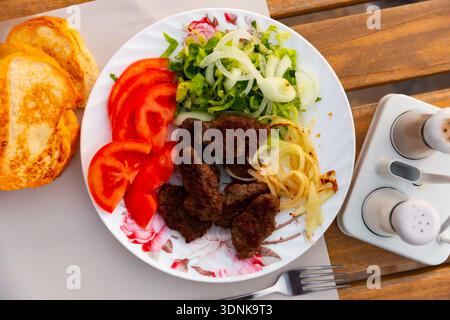 Türkische Kofte, gegrillte Kalbfleischbällchen mit Gemüse und Brot Stockfoto