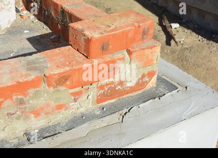 Nahaufnahme der feuchtigkeitsfesten Membran auf den Fundamentwänden. Wasserdichte Bitumenmembran für den Hausgründungsbau. Stockfoto